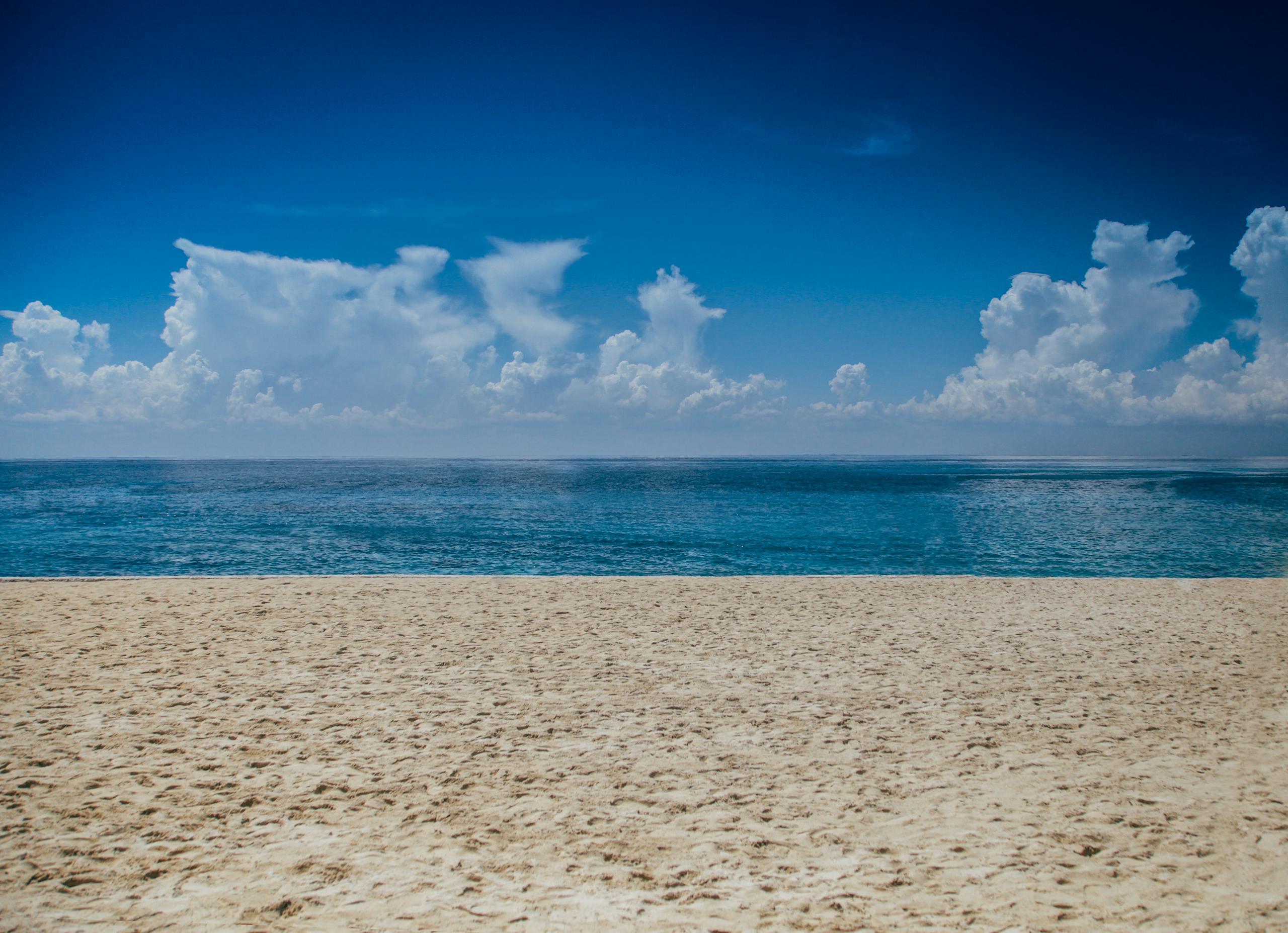 A tranquil beach scene with clear skies and gentle ocean waves, perfect for relaxation.